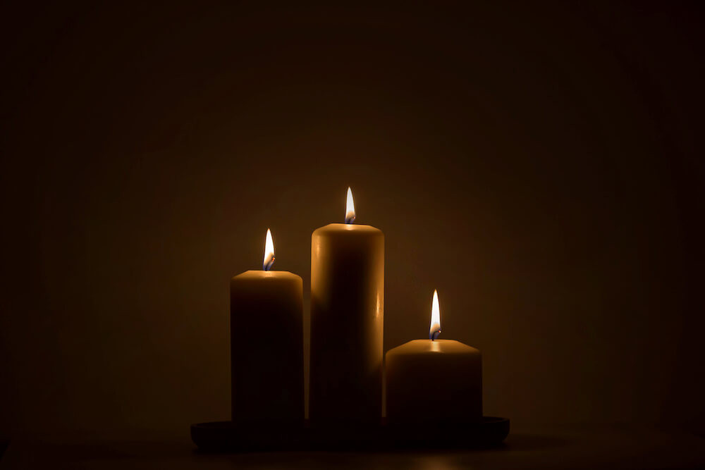 Three candles burning brightly in the dark Candles on the dark background